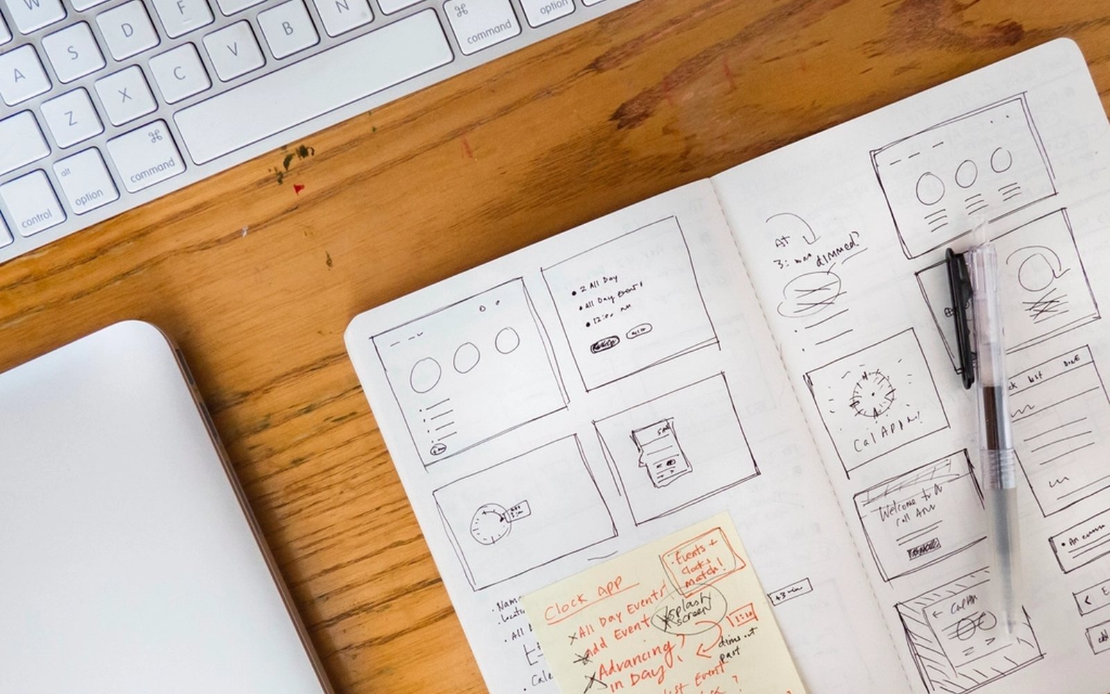 Hand-drawn website wireframe sketches on a notepad beside a keyboard.