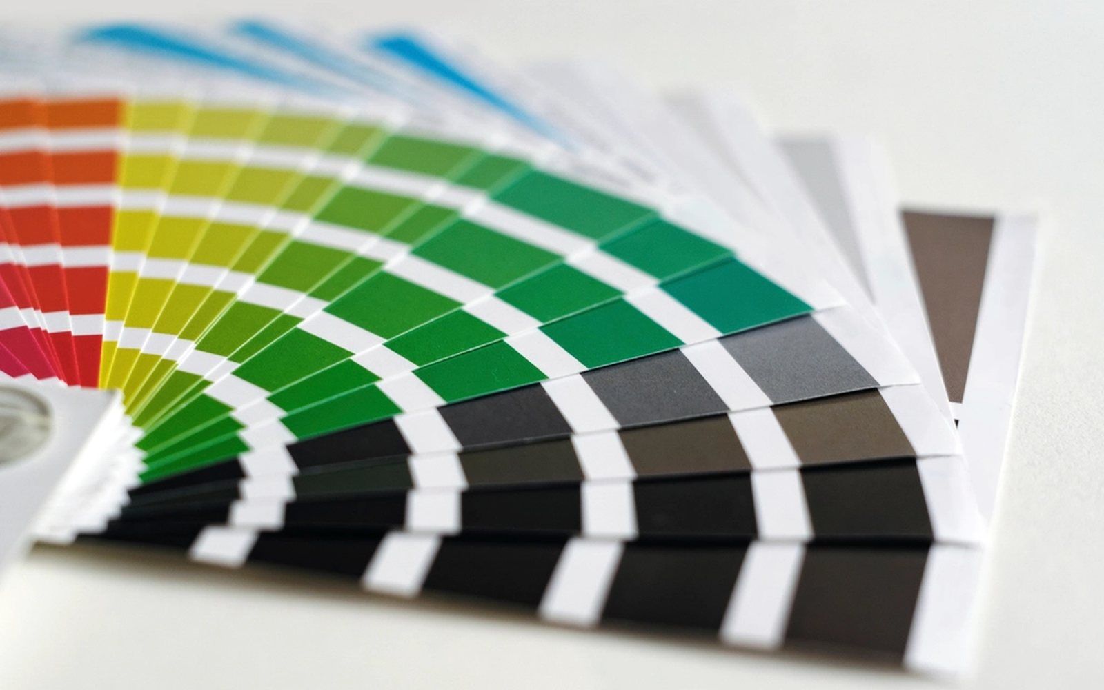 Fanned-out printed colour swatch guide on a desk.