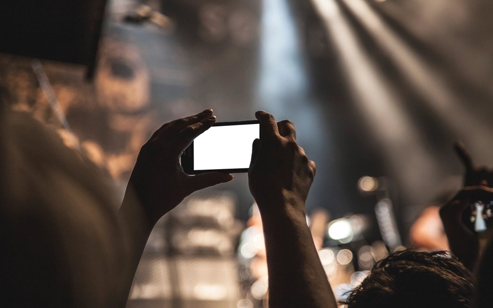Hands holding a phone to film an event.